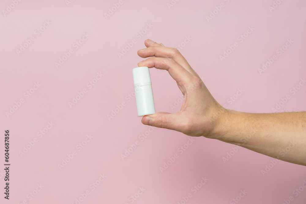 Drops bottle for eye or ear in hand on pink background. Pharmaceutical product. Copy space. Drops bottle for eye or ear in hand on pink background. Pharmaceutical product. Copy space.