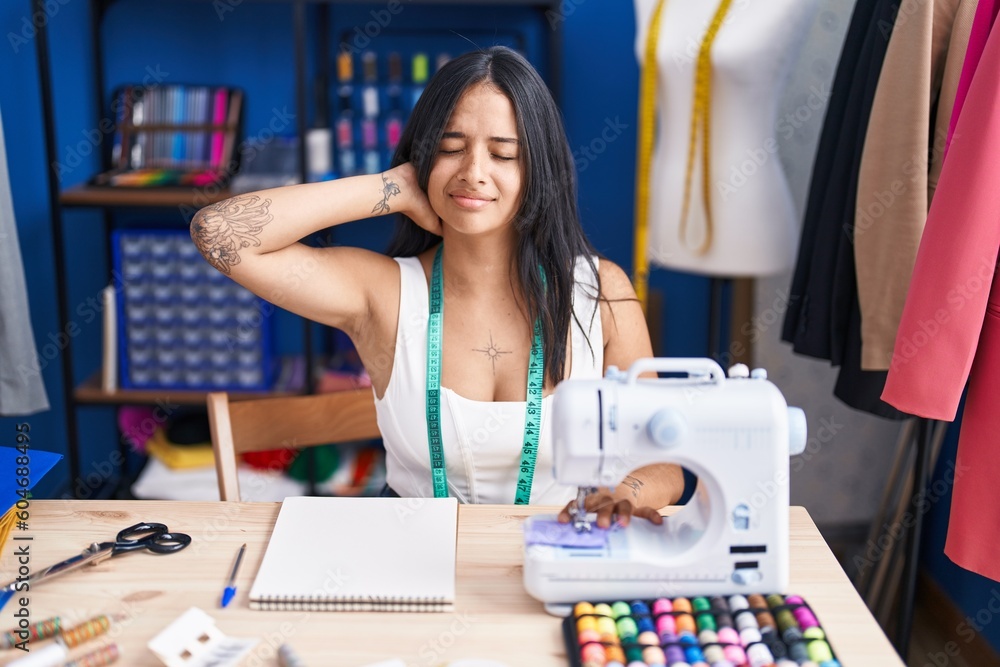 Fototapeta premium Young hispanic woman tailor stressed using sewing machine at sewing studio