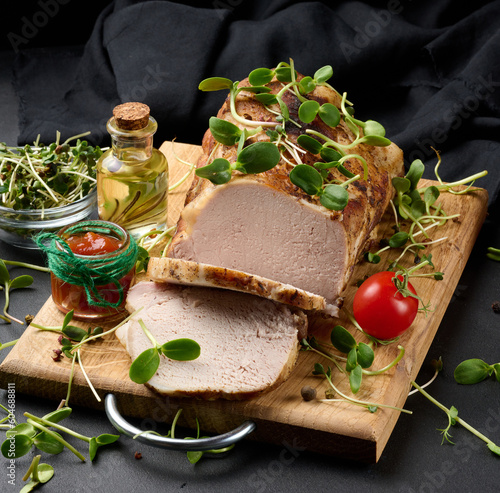 Baked piece of pork balyk on the table with spices. Tenderloin cut into pieces photo