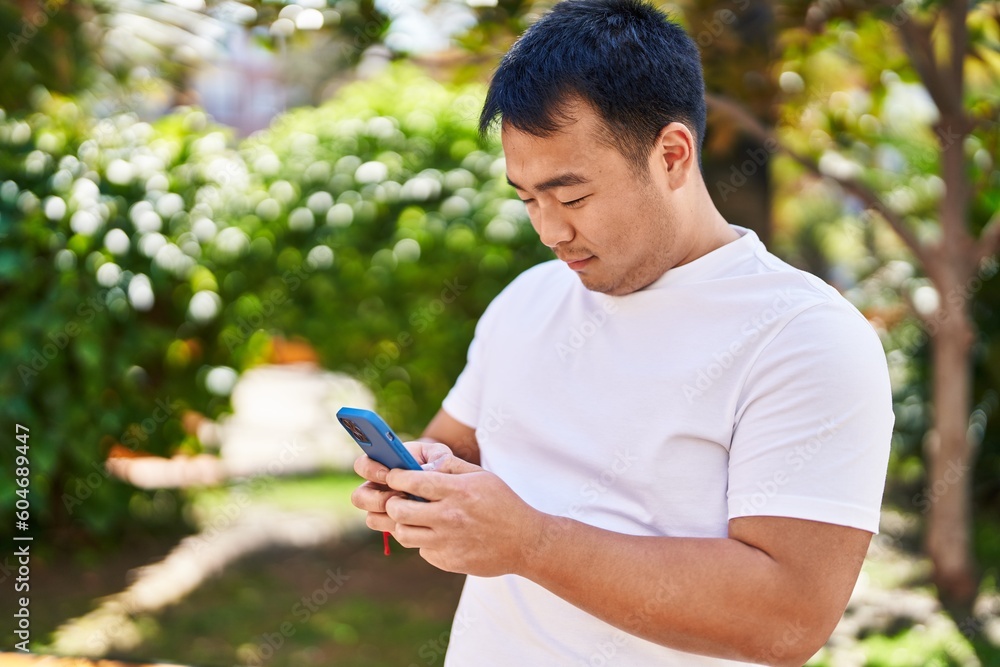Young chinese man smiling confident using smartphone at park Young chinese man smiling confident using smartphone at park