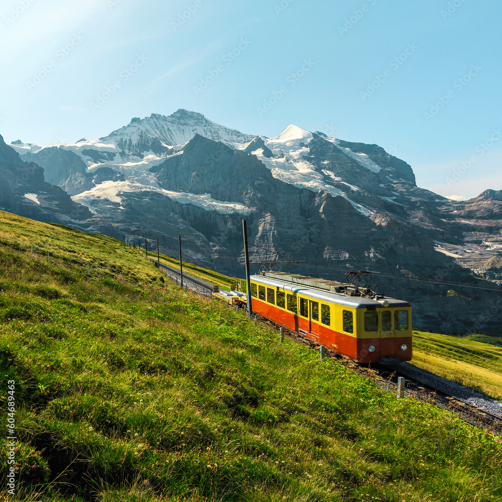 Small retro tourist train and snowy mountains in background, Switzerland