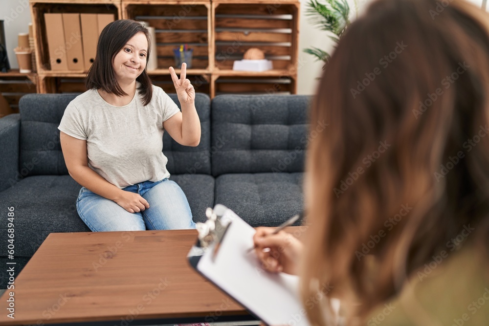 Hispanic girl with down syndrome doing therapy smiling with happy face winking at the camera doing victory sign. number two. Hispanic girl with down syndrome doing therapy smiling with happy face winking at the camera doing victory sign. number two.