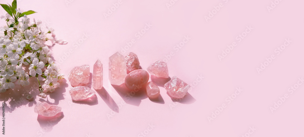 set of rose quartz minerals and spring white flowers on pink abstract background. Gemstones for Healing Crystal Ritual. esoteric spiritual practice for aura cleansing, relax, harmony. banner - obrazy, fototapety, plakaty 
