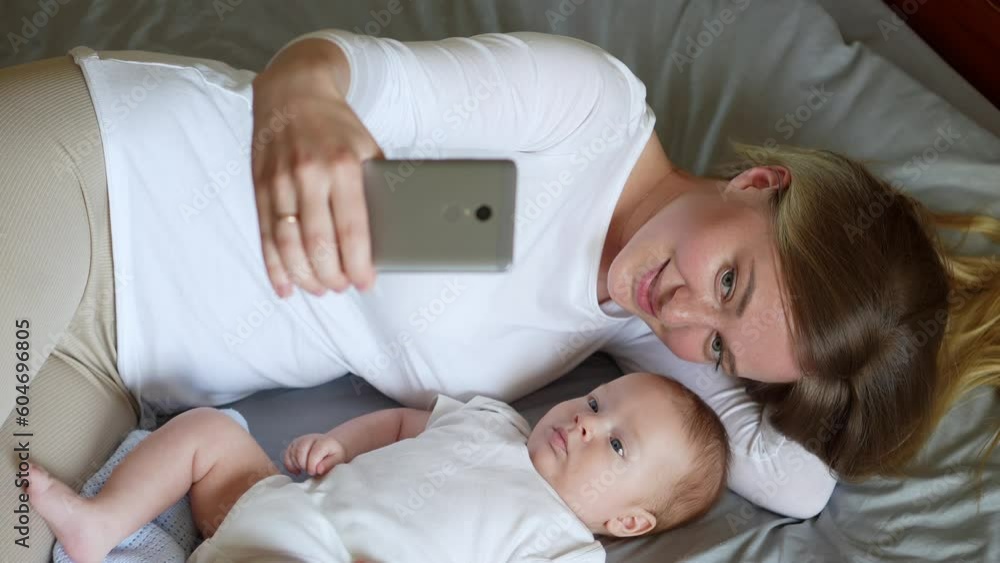 Mother and baby in bed, looking at the camera, taking a selfie.Young family communication online, video call, technology Mother and baby in bed, looking at the camera, taking a selfie.Young family communication online, video call, technology