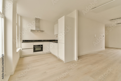 an empty room with wood flooring and white cupboards on either side of the room  there is a stove in the corner
