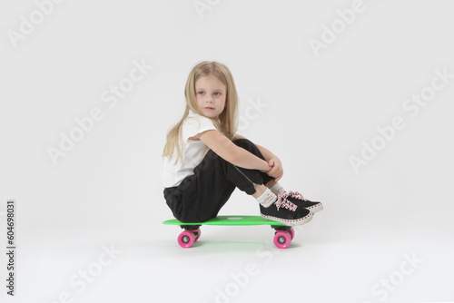 Studio portrait of beautiful blonde little girl with skateboard