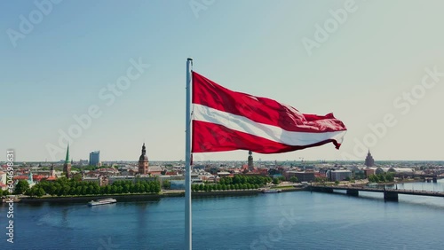 Huge Latvian flag flutters in the wind with Riga old town in the background in Latvia. Beautiful summer day. photo
