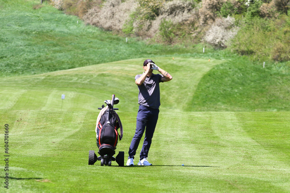 Man golfer with rangefinder on golf course - obrazy, fototapety, plakaty 