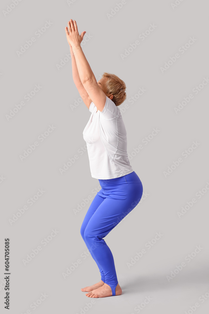 Sporty mature woman practicing yoga on light background Sporty mature woman practicing yoga on light background