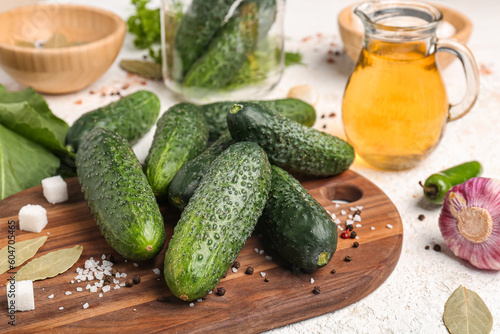 Wooden board with fresh cucumbers for preservation on light background