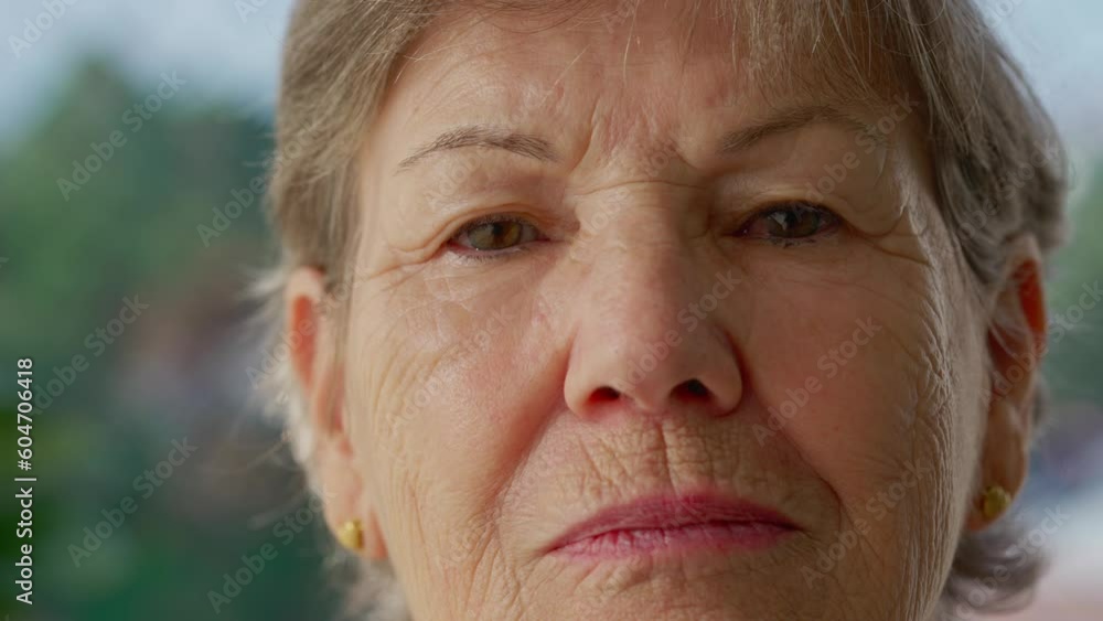 Portrait of a serious older woman close-up face looking at camera. Older female person with stoic expression Portrait of a serious older woman close-up face looking at camera. Older female person with stoic expression