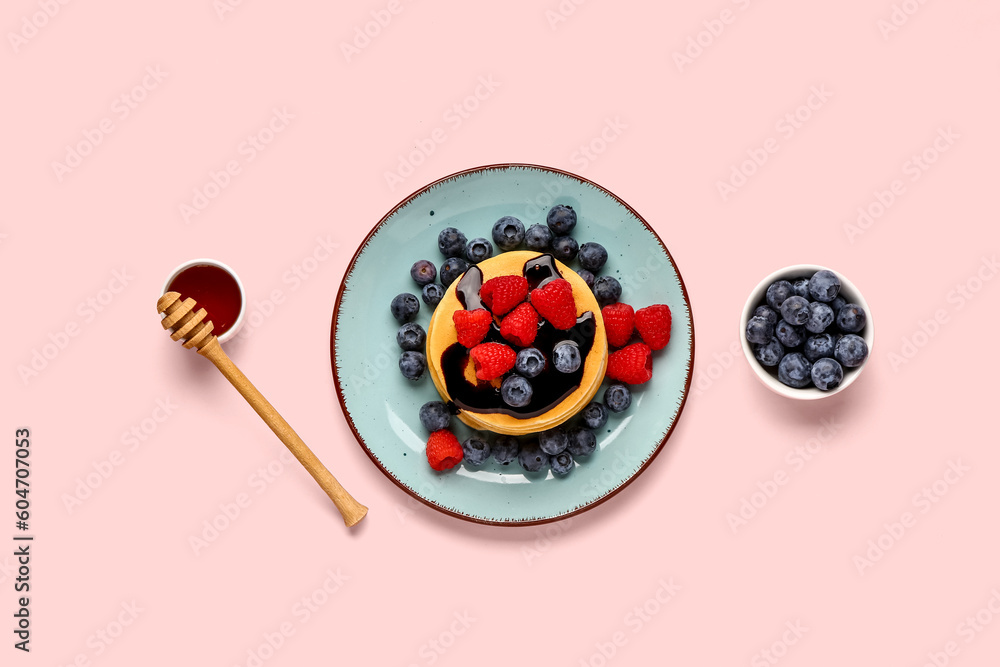 Plate with sweet pancakes and berries on pink background Plate with sweet pancakes and berries on pink background