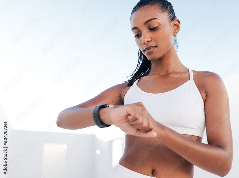 Slim female athlete looking at smartwatch. Woman in white fitness clothes standing outdoors checking her heart rate. Slim female athlete looking at smartwatch. Woman in white fitness clothes standing outdoors checking her heart rate.
