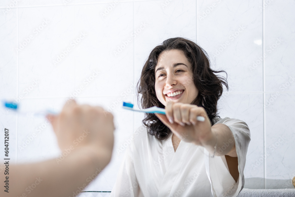 portrait of a pretty young latin girl holding a toothbrush and smiling in front of the mirror. having proper oral hygiene makes you feel happier portrait of a pretty young latin girl holding a toothbrush and smiling in front of the mirror. having proper oral hygiene makes you feel happier