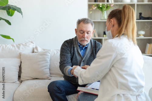 Female doctor senior man taking his blood pressure in doctor office or at home. Old man patient and doctor have consultation in hospital room. Medicine healthcare medical checkup. Visit to doctor