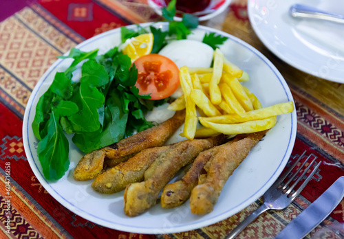 Portion of fried red mullet served with french fries, lemon and greens, typical dish of Turkey