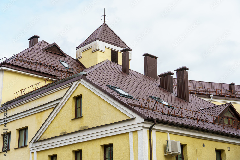 The facade of an old building with a red roof after repair and reconstruction. Red tiled roof on a low building in the historical center of the city.