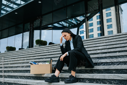 woman sitting on steps, lost in thought about her jobless situation and the difficulty of finding work after dismissal. A visual representation of job loss and worklessness photo