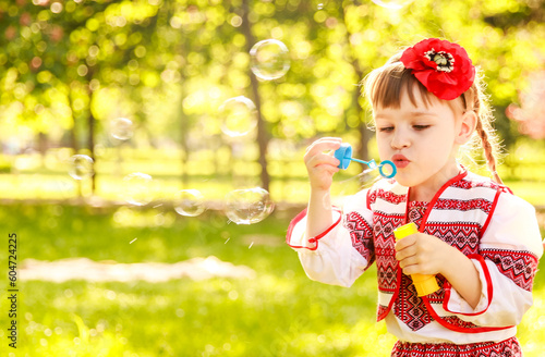 Girl blowing soap bubbles. A girl with a red poppy in her hair. A child in a national Ukrainian costume. Children in Ukraine. 