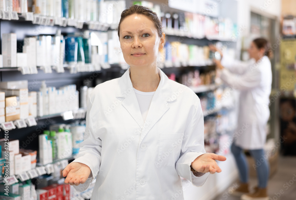 Adult female pharmacist in medical uniform posing while working in pharmacy
