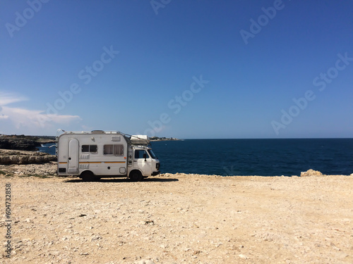 A camper on a beach. Sea and blue sky in the background.