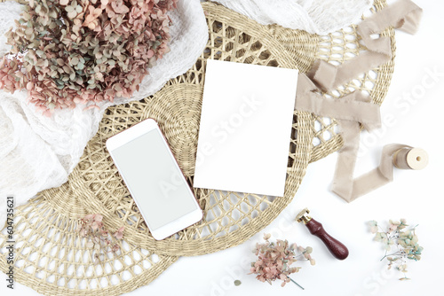 5x7 invitation greeting card, smart phone eVite. Wedding stationery suite mock-up styled with boho decor, dried hydrangea flowers bouquet, rattan lace mats, vintage wax seal, and silk ribbon.