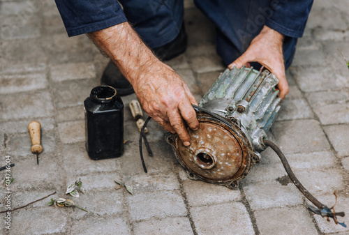 Tableau sur toile Male professional, electrician, electromechanic repairing an old rusty electric motor
