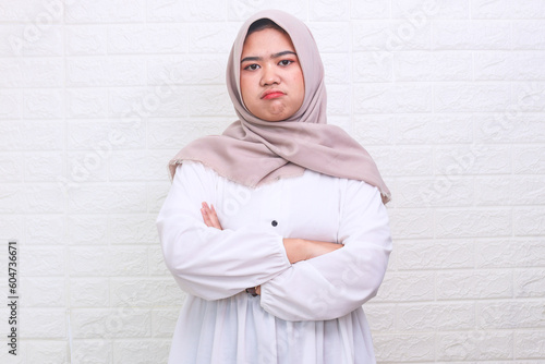 Asian Muslim woman angry jealous with crossed arms isolated over white background. Expression and gesture concept. 