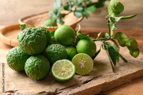 Kaffir lime and lime fruit on wooden background, Organic ingredients in Thai cuisne, beauty and cosmetics © nungning20