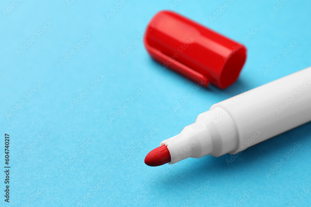 Naklejka premium Bright red marker on light blue background, closeup. Space for text