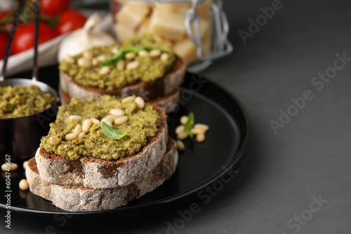 Tasty bruschettas with pesto sauce and nuts on dark grey table, closeup. Space for text