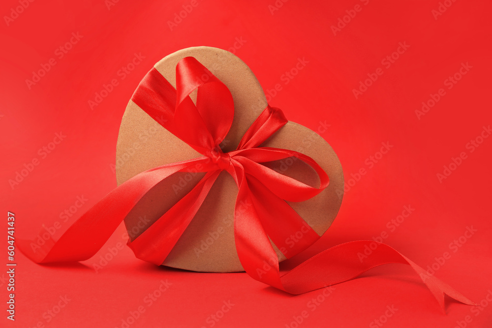 Beautiful heart shaped gift box with bow on red background Beautiful heart shaped gift box with bow on red background