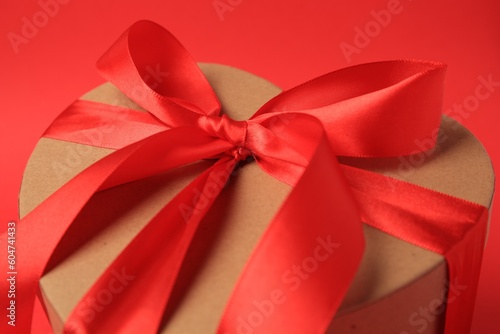 Beautiful heart shaped gift box with bow on red background, closeup