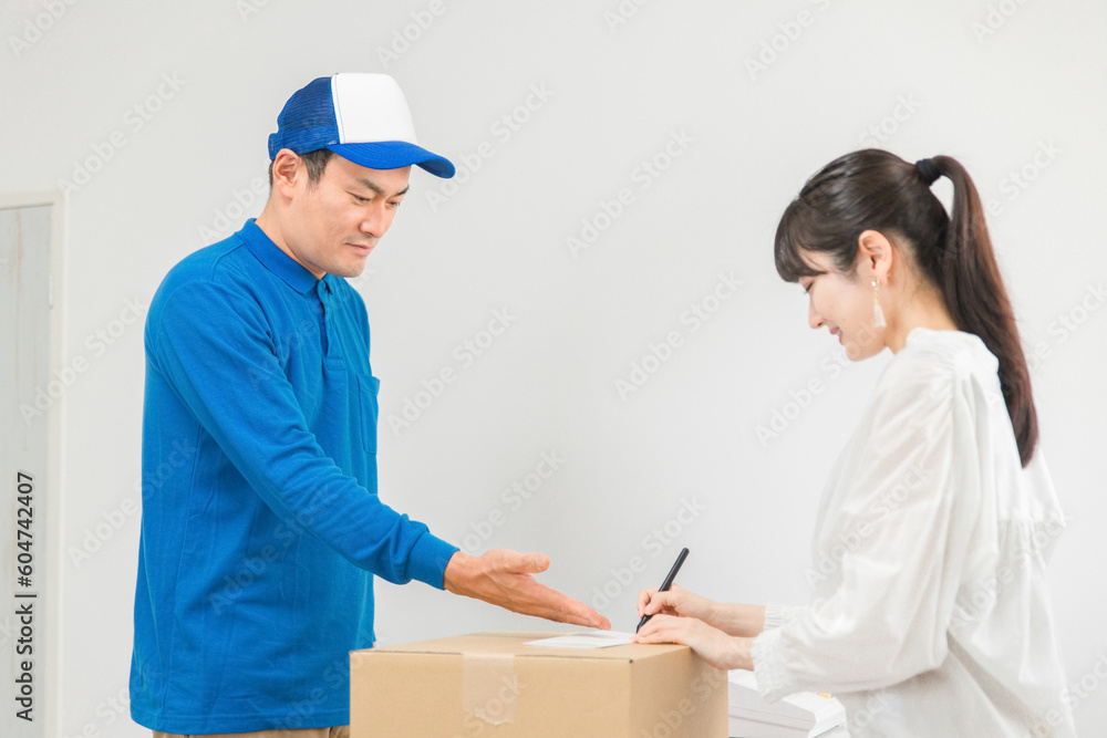 荷物を届ける配達員の男性と受け取る・サインする女性
荷物を届ける配達員の男性と受け取る・サインする女性