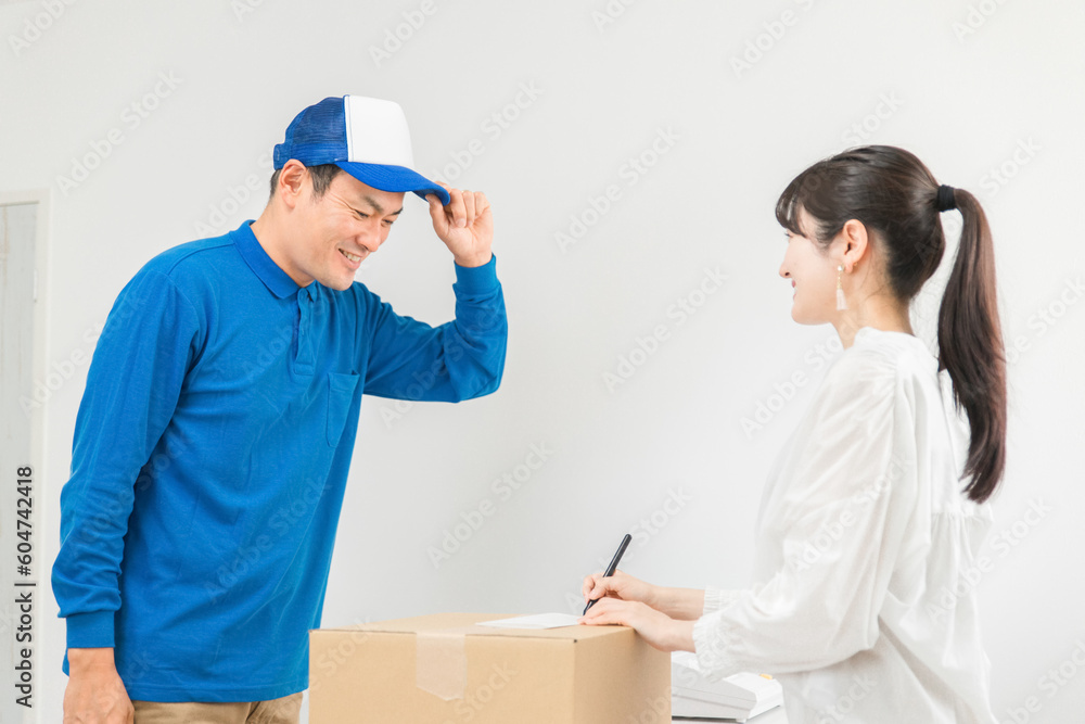 荷物を届ける配達員の男性と受け取る・サインする女性
荷物を届ける配達員の男性と受け取る・サインする女性