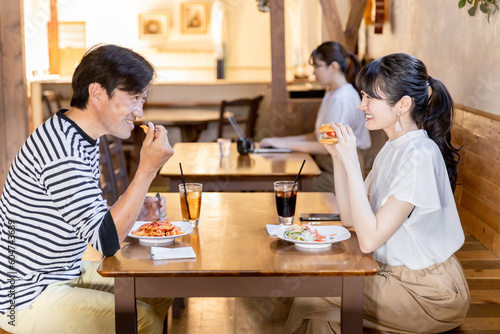 カフェでおしゃべりしながらランチをするアジア人の男女 