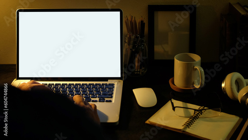 View over man shoulder hands typing on keyboard of laptop computer at desk.