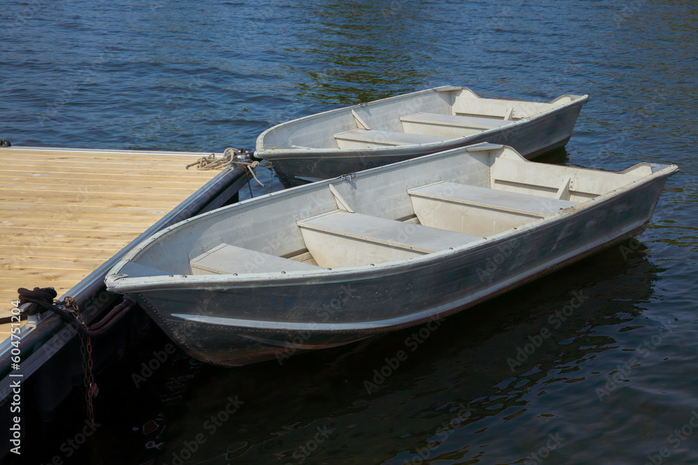 two rowboats on the edge of a dock on a calm lake aluminum boats recreation two rowboats on the edge of a dock on a calm lake aluminum boats recreation