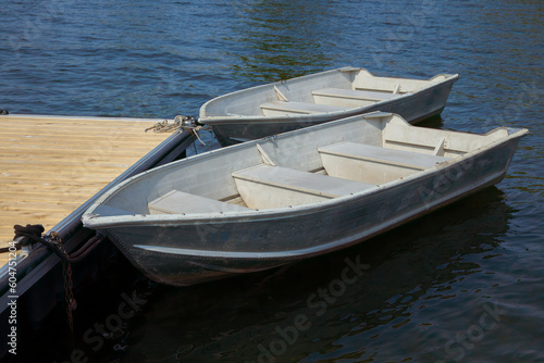 two rowboats on the edge of a dock on a calm lake aluminum boats recreation © Jacques Durocher
