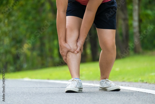 Close-up of young female athlete having knee pain after exercise. Female athlete having leg pain while exercising in park. Exercise injury concept
