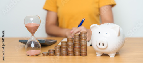 Money Saving for Future Plan, Retirement fund, Pension, Investment, Wealth Business and Financial concepts. woman with coins stack, piggy bank and sandglass for money Counting and deposit