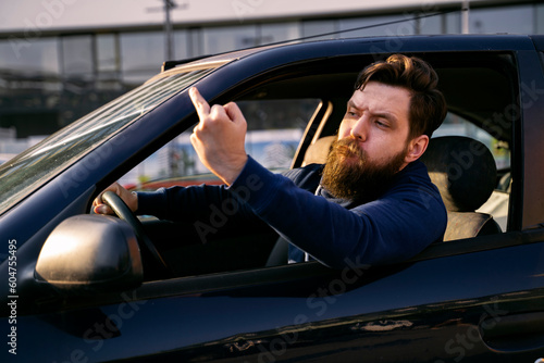 Man expressing negative emotions from the car flipping middle finger to other driver, road rage  photo