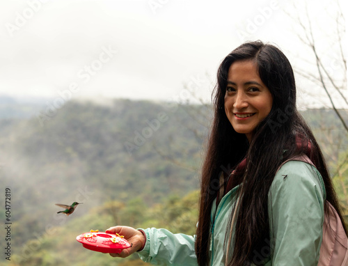 mujer soven sonriendo observando aves de colores colibries