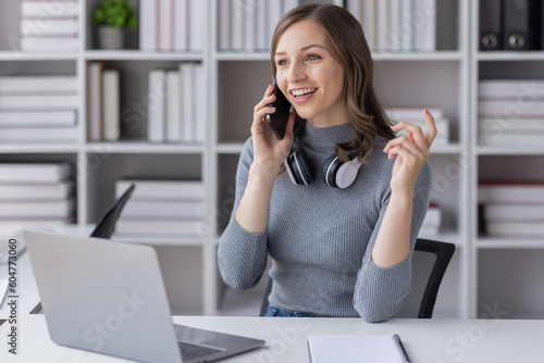 Young adult happy smiling Hispanic Asian student wearing headphones talking on online chat meeting using laptop in university campus or at virtual office. College female student learning remotely. 