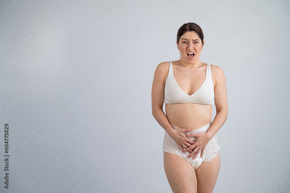 A woman in adult diapers holds her hands on her stomach. Urinary incontinence problem. A woman in adult diapers holds her hands on her stomach. Urinary incontinence problem.