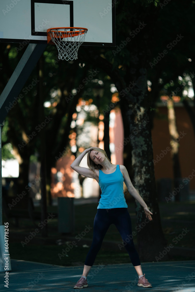 Woman exercises on an outdoor basketball court.