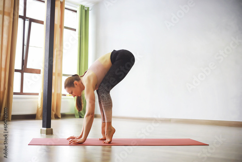 Yoga instructor showing asana in studio on the rug. Mat and a beautiful yoga woman. Morning yoga, yoga practice concept