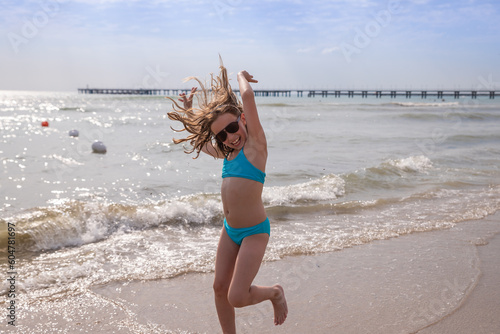 girl has a swimsuit, having fun alone on the sand in summer by the sea. female child dancing by the water while on holiday or vacation.happy and smiling girl performs gymnastic, dance exercises