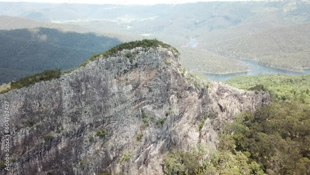 Aerial fly toward the mountain peak of Pages Pinnacle, ending in a southernly view down the ridge of the peak towards the trees below. Aerial fly toward the mountain peak of Pages Pinnacle, ending in a southernly view down the ridge of the peak towards the trees below.