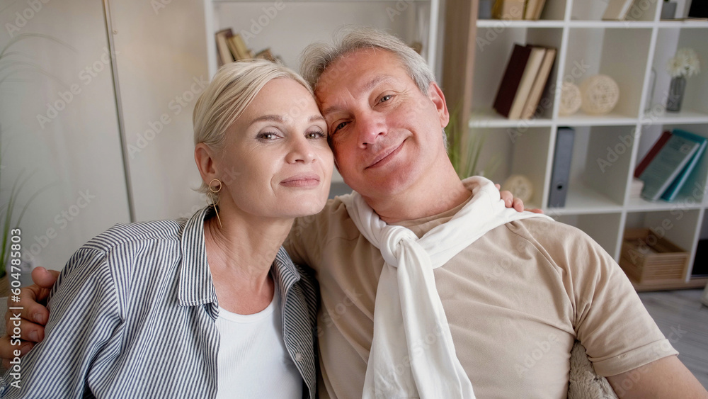 Love forever. Family couple. Enjoying moment. Happy middle-aged man and woman embracing together sitting sofa in light home interior. Love forever. Family couple. Enjoying moment. Happy middle-aged man and woman embracing together sitting sofa in light home interior.